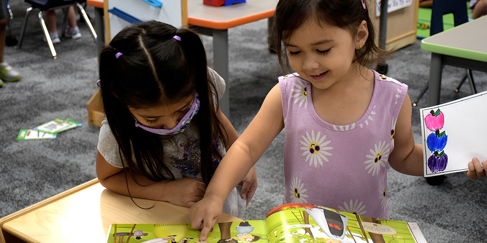 two Pre-K students read a book together