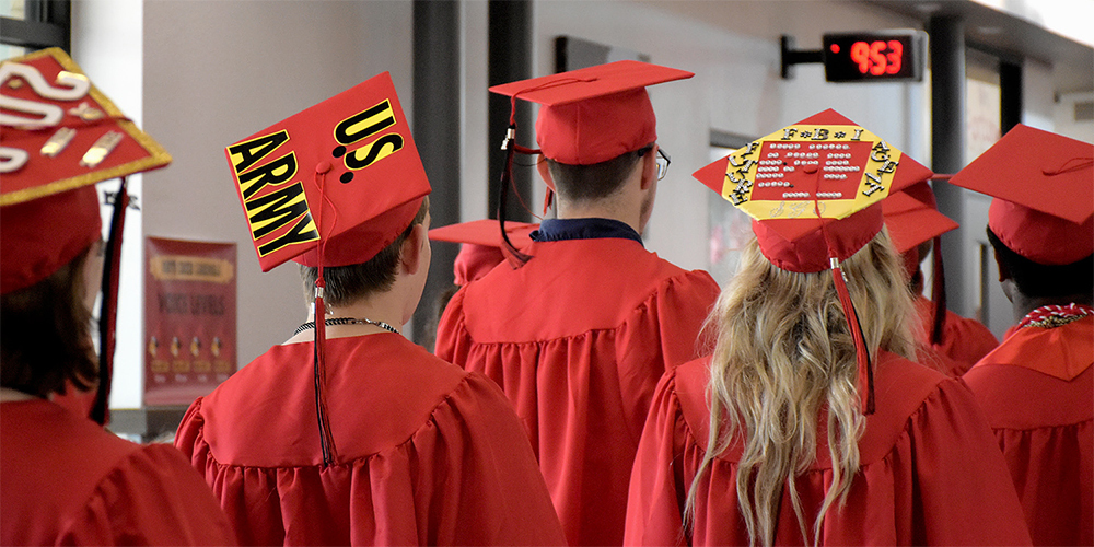 Seniors walk down the hallway of an elementary school wearing their graduation caps and gowns