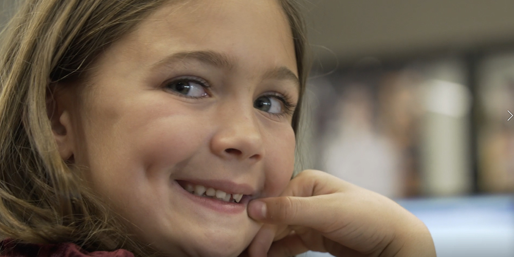 a young student smiles of their shoulder in the classroom