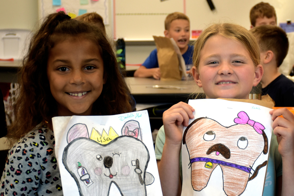 Two students in Mrs. Schneider's class hold up their "tooth fairy" pillow designs