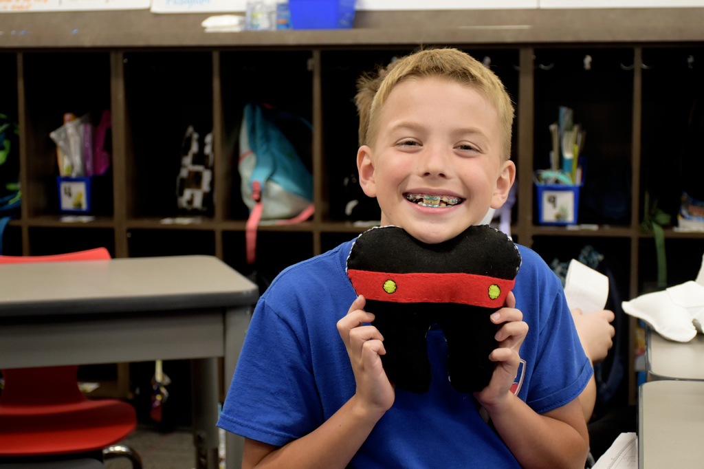 A student holds up his tooth fairy pillow sewn by a high school student