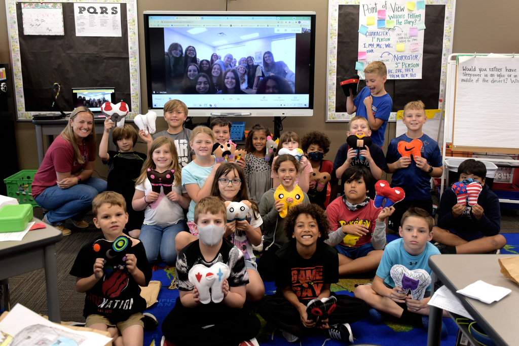 Students in Mrs. Schneider's class hold up their tooth fairy pillows while students in Mrs. Tyner's class are shown on a Google Meet video in the background